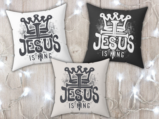 Three pillows with 'Jesus is King' text on a wooden surface with string lights.