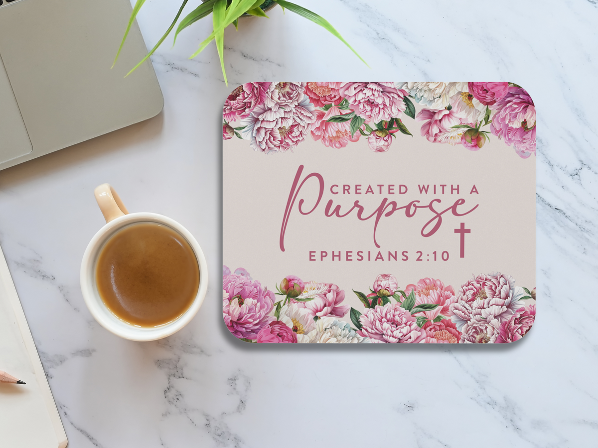 Marble desk with coffee cup, laptop, plant, and floral mouse pad. The pad reads "Created with a Purpose, Ephesians 2:10" with pink flowers.