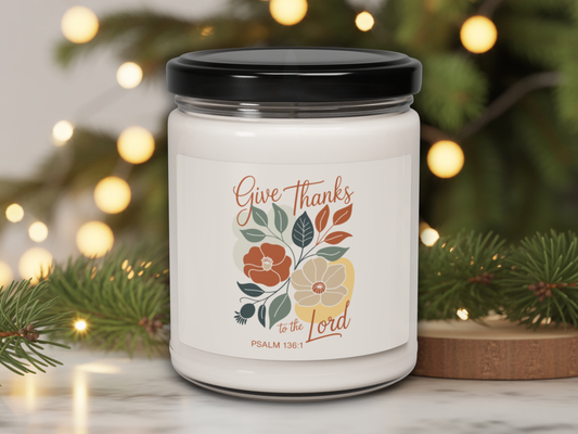 Candle jar with 'Give Thanks to the Lord' text and floral design against a festive background