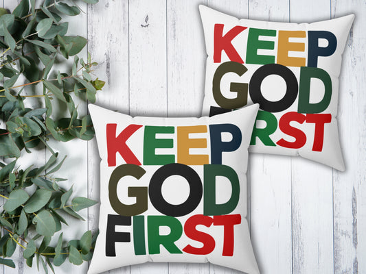 Two pillows with 'KEEP GOD FIRST' text on a wooden surface with greenery.