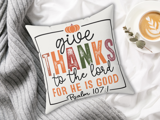 Scripture throw pillow with multicolor “Give Thanks” design styled on bed with gray knit blanket and latte.