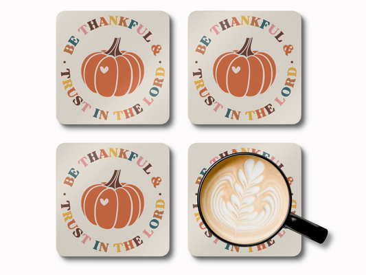 Set of four “Be Thankful & Trust in the Lord” pumpkin coasters with latte art coffee cup.