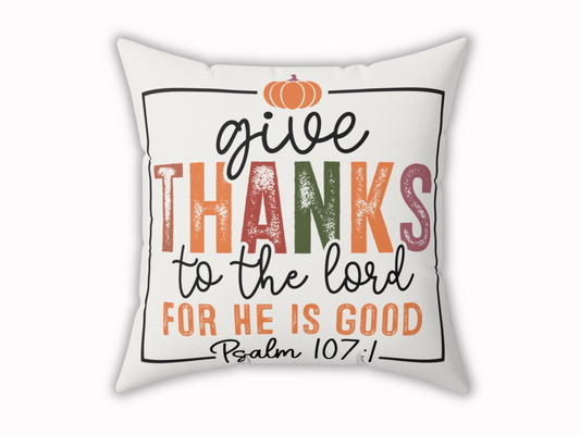 White square pillow with colorful scripture design reading “Give Thanks to the Lord, for He is Good – Psalm 107:1” topped with a pumpkin.