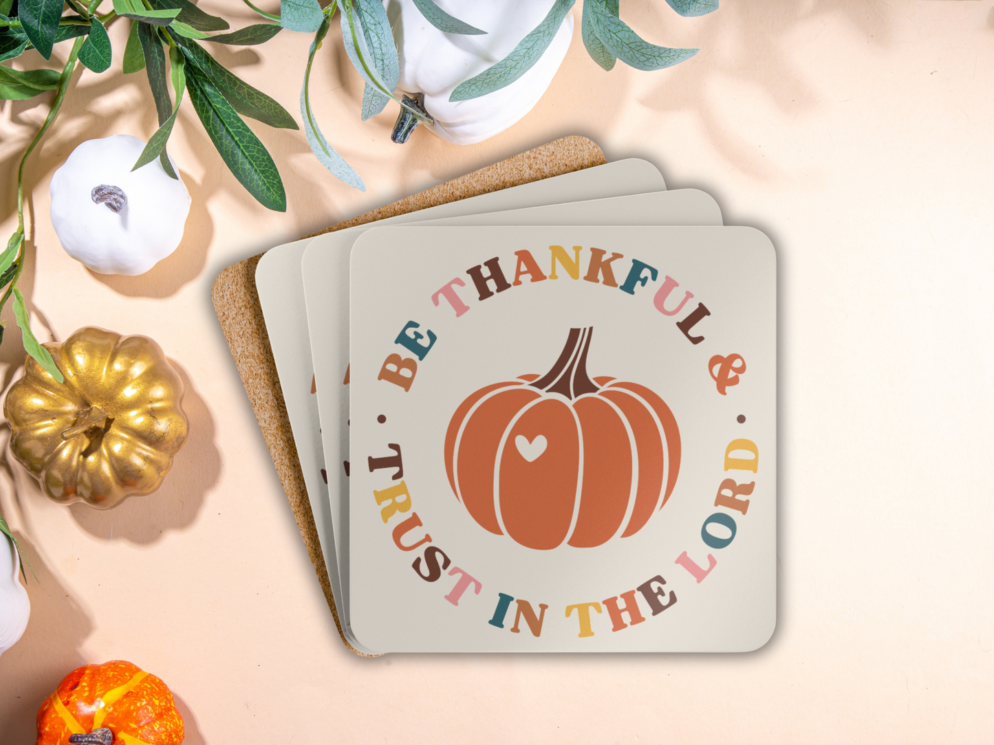 Stack of Christian pumpkin coasters with cork backing styled with white, gold, and orange pumpkins.