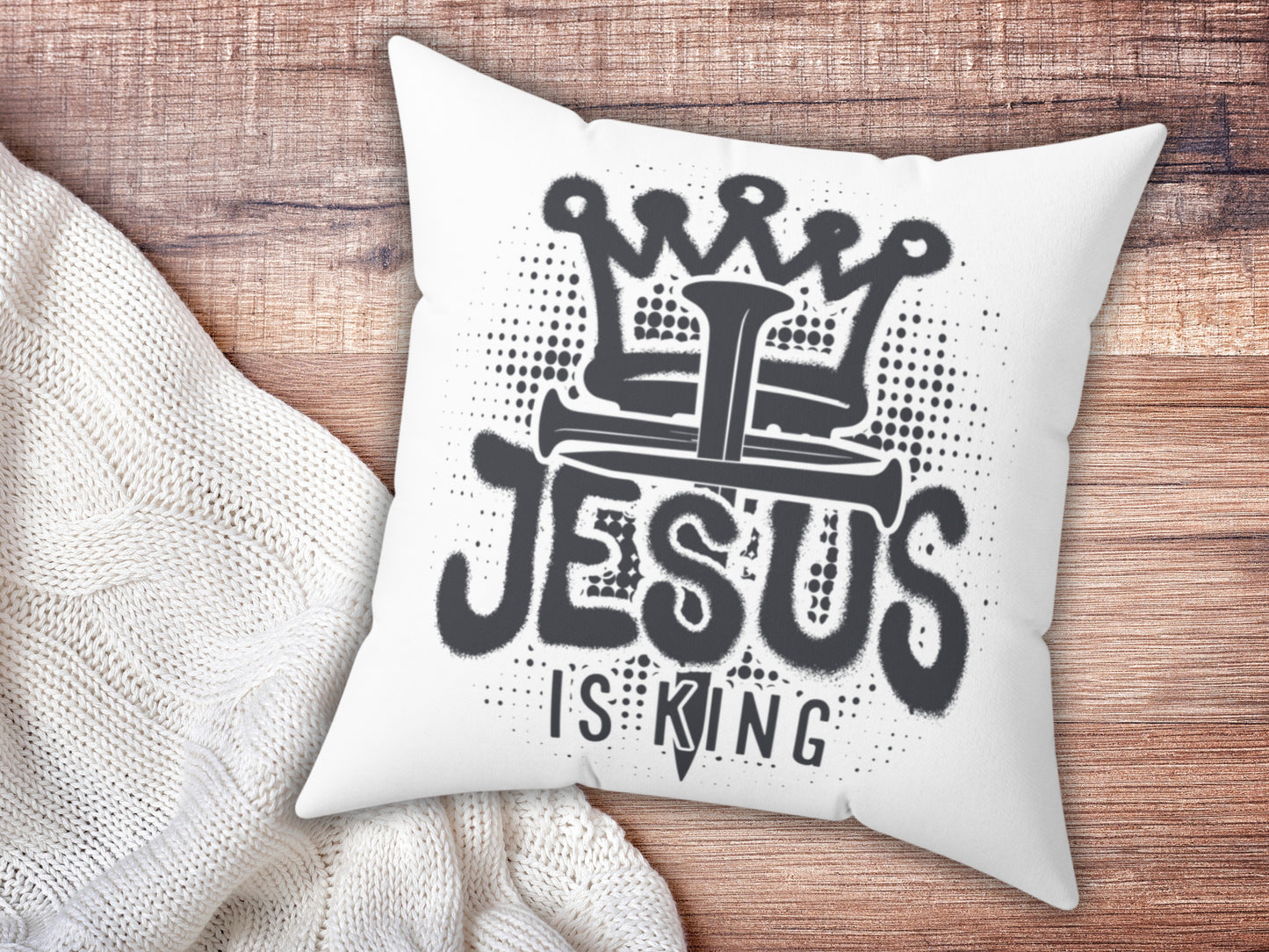 White pillow with 'Jesus is King' text on a wooden surface