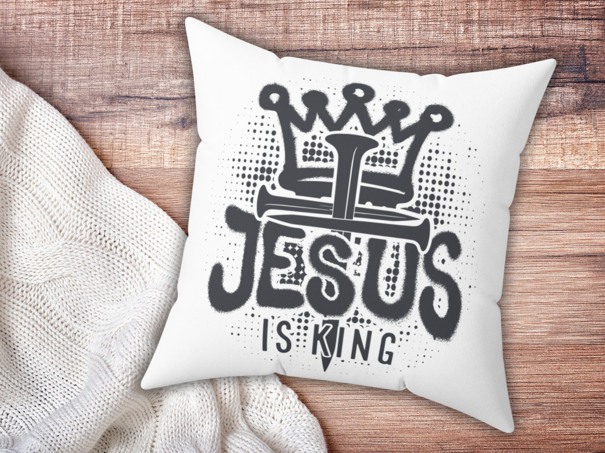 White pillow with 'Jesus is King' text on a wooden surface