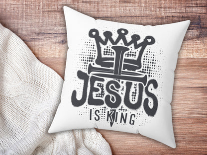 White pillow with 'Jesus is King' text on a wooden surface
