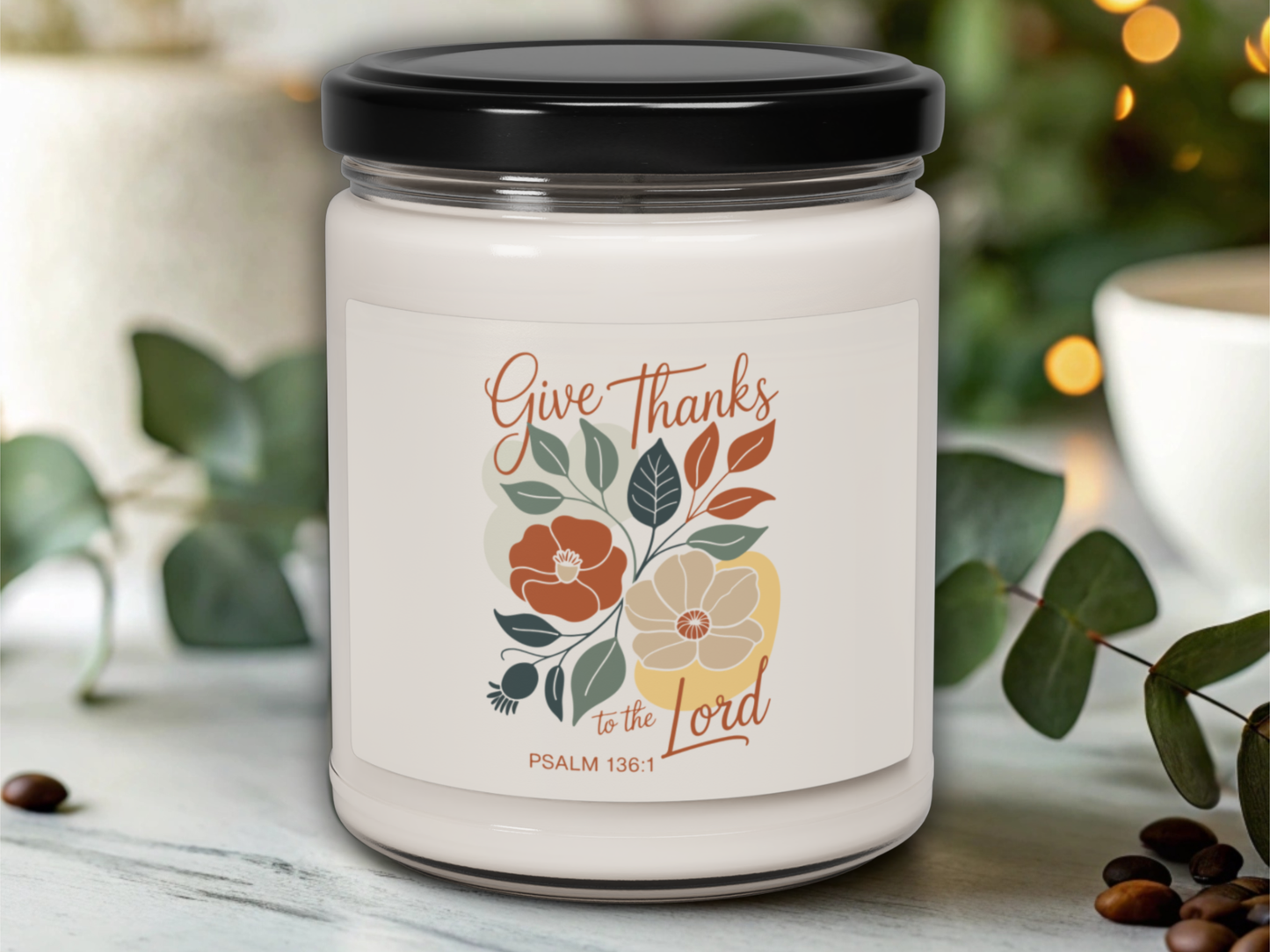 Candle jar with 'Give Thanks to the Lord' text and floral design on a blurred background