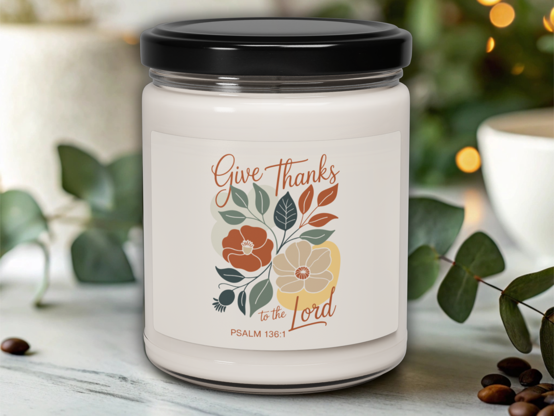 Candle jar with 'Give Thanks to the Lord' text and floral design on a blurred background