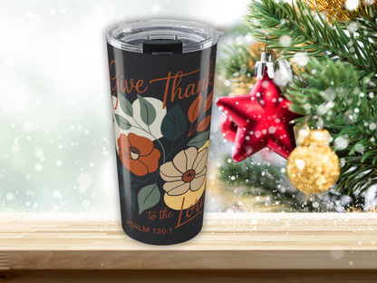 Tumbler with floral design and text in front of a Christmas tree with ornaments.