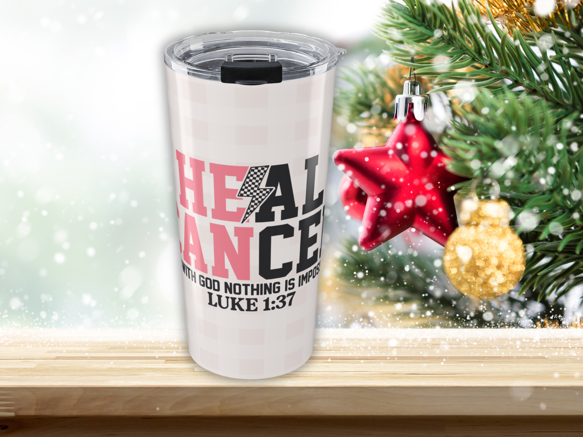 Pink plaid tumbler with motivational quote in front of Christmas decorations