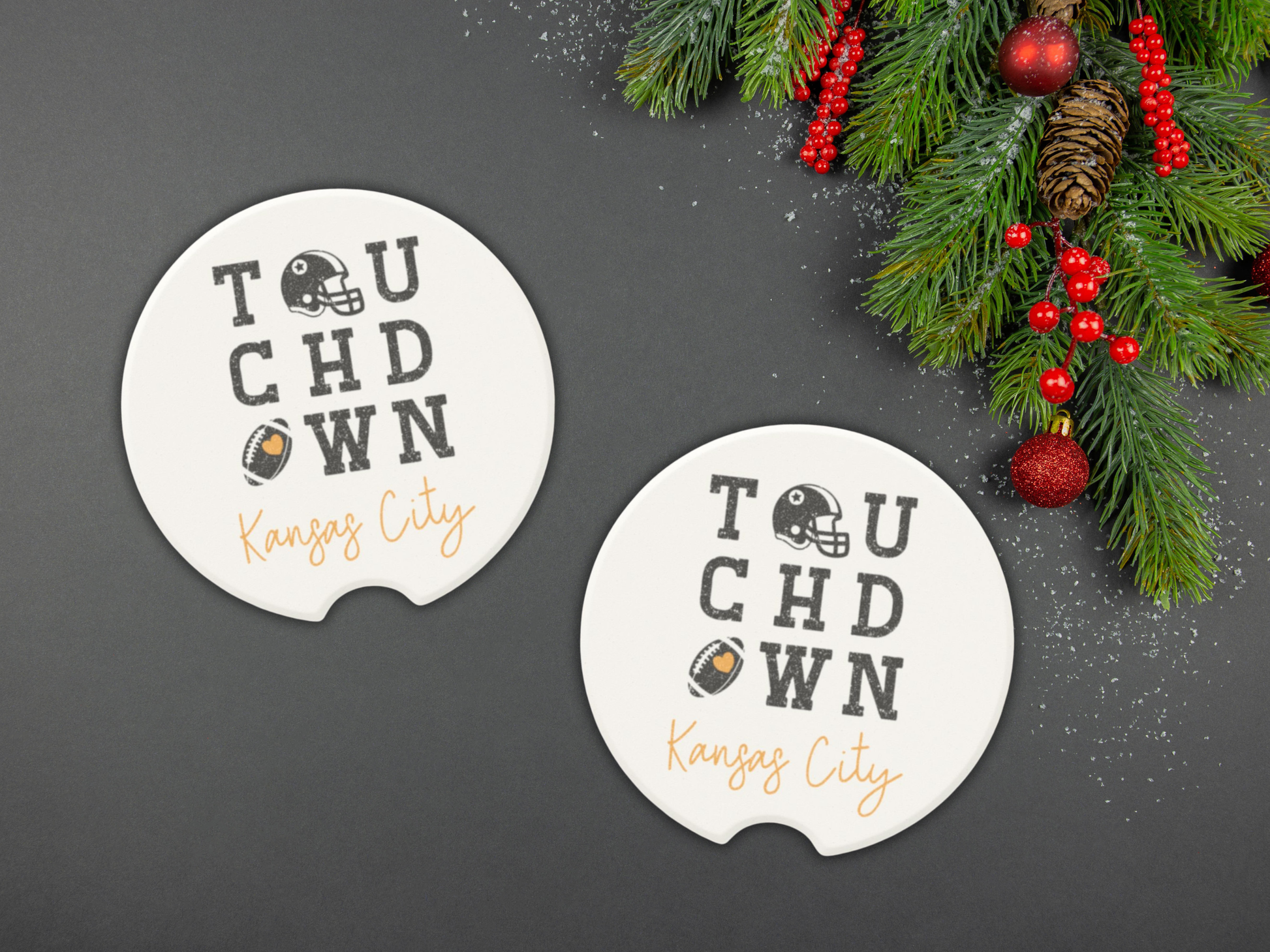 Two 'Touchdown Kansas City' coasters on a dark surface with Christmas decorations.
