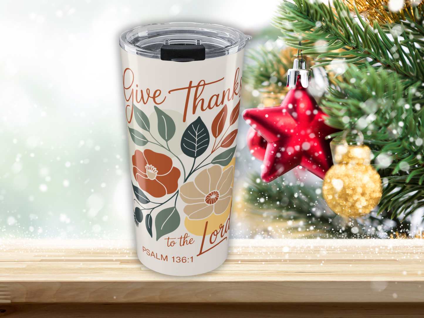 Tumbler with 'Give Thanks to the Lord' design in front of a Christmas tree.