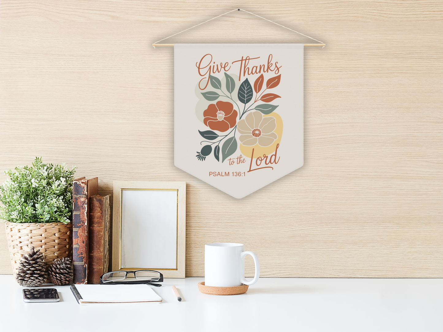 Decorative wall hanging with floral design and text on a wall above a desk.