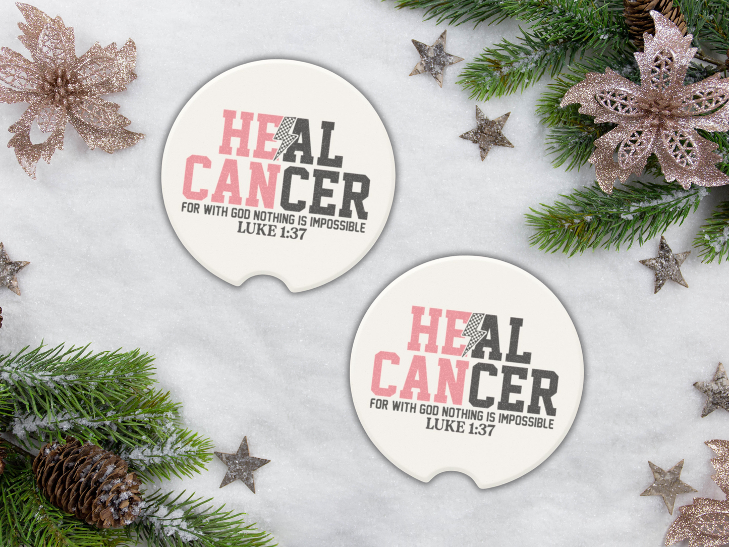 Two 'HEAL CANCER' car coasters with Christmas decorations on a snowy background