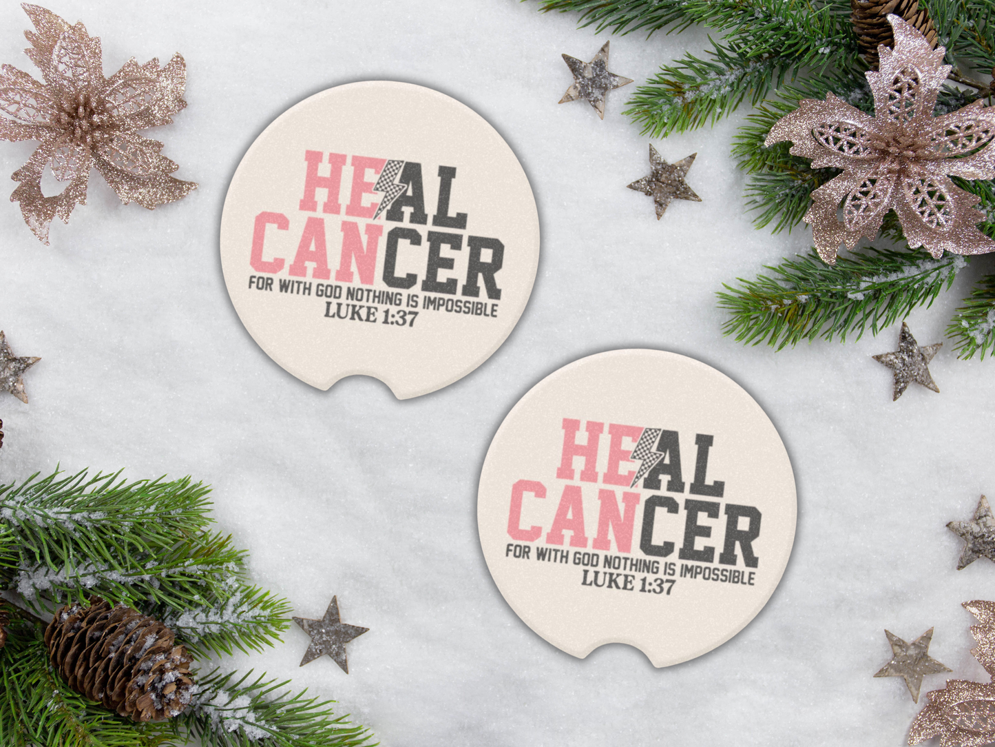 Two pink car coasters with 'HEAL CANCER' text on a snowy background with Christmas decorations.