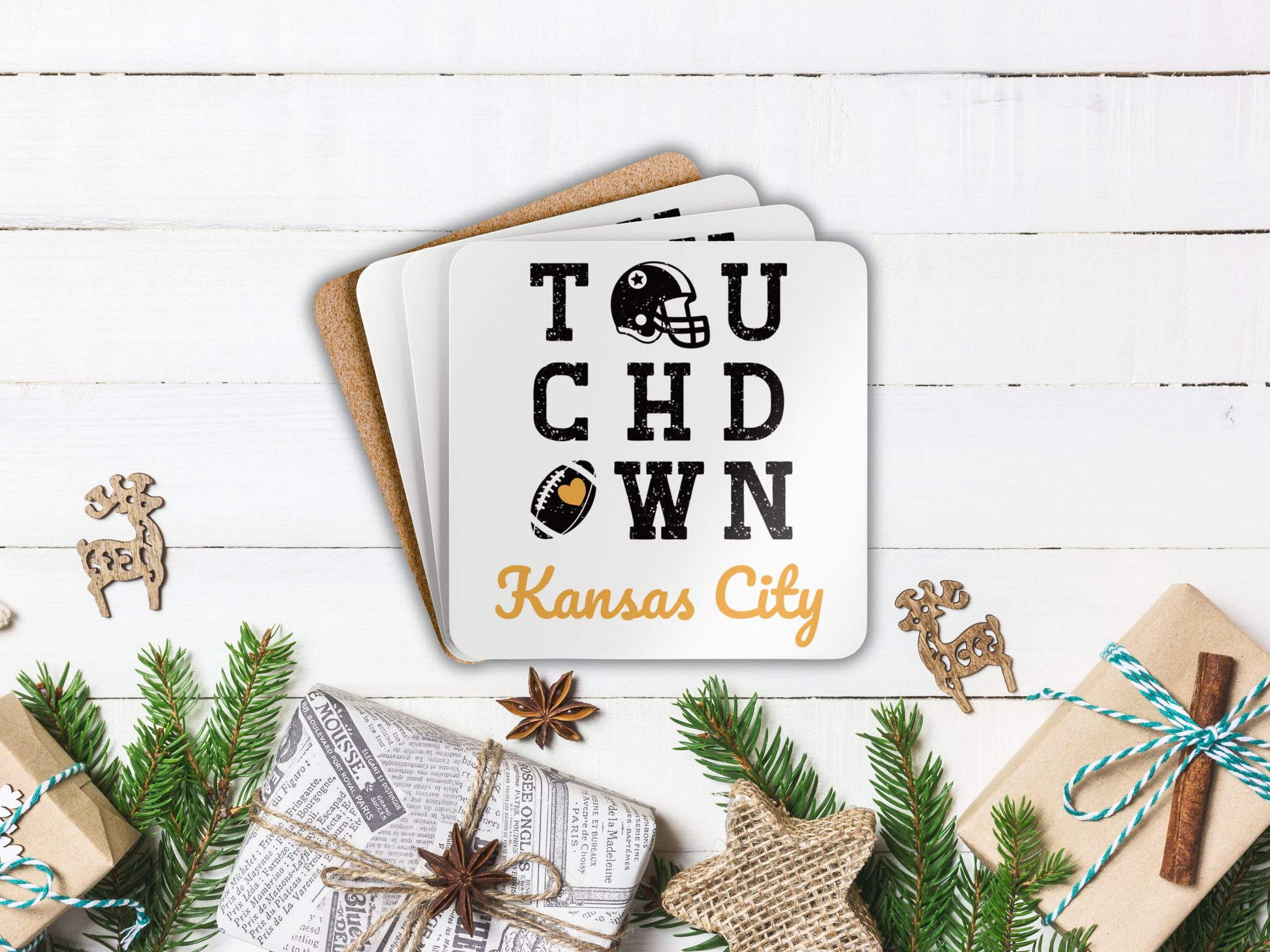 Stack of coasters with 'Touchdown Kansas City' design on a wooden surface with Christmas decorations.