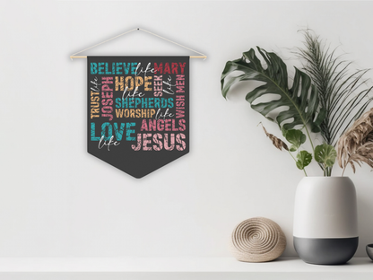 Decorative wall hanging with colorful text on a white wall with plants and a vase.