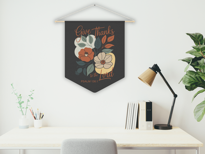 Decorative wall hanging with floral design and text above a desk with a lamp and books.