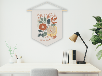 Decorative wall hanging with floral design and text above a desk with a lamp and books.