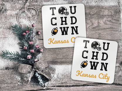 Two 'Touchdown Kansas City' coasters on a wooden surface with decorative elements.