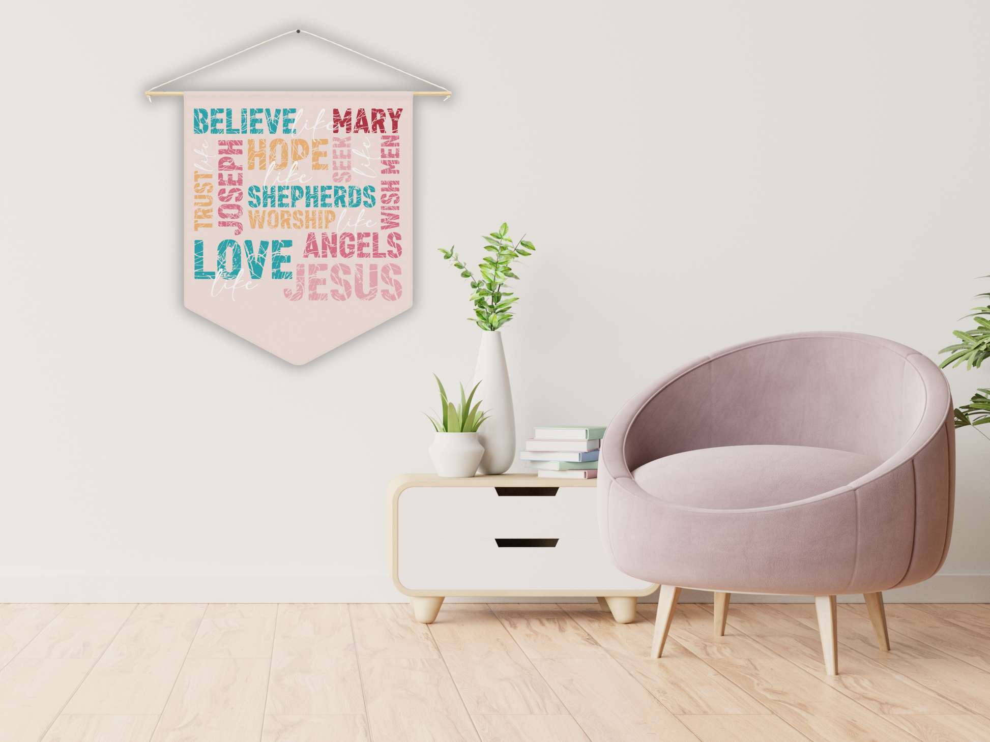 Decorative wall hanging with colorful text in a living room setting with a pink chair and white cabinet.