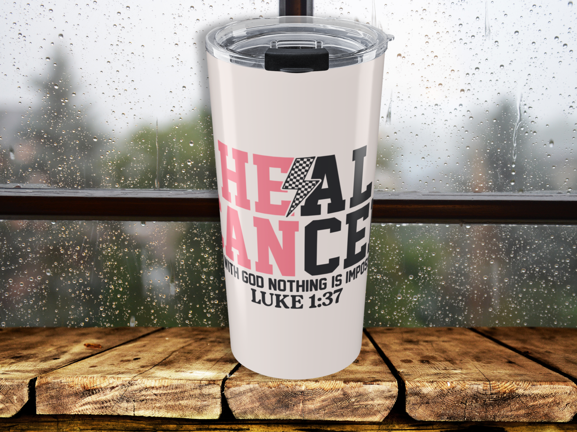 Pink tumbler with motivational quote on a wooden surface with a blurred background