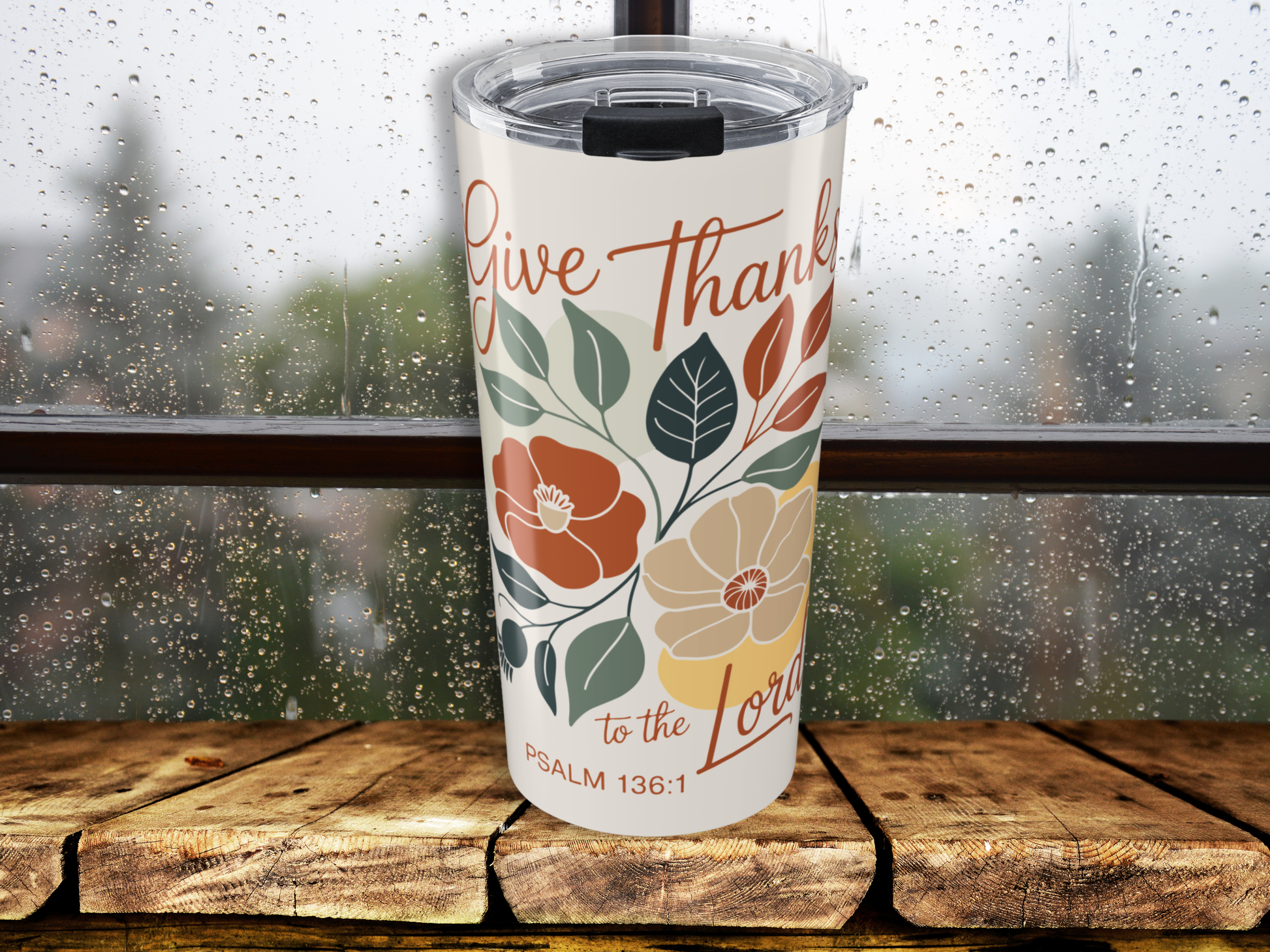 Tumbler with floral design and text on a wooden surface with a blurred background