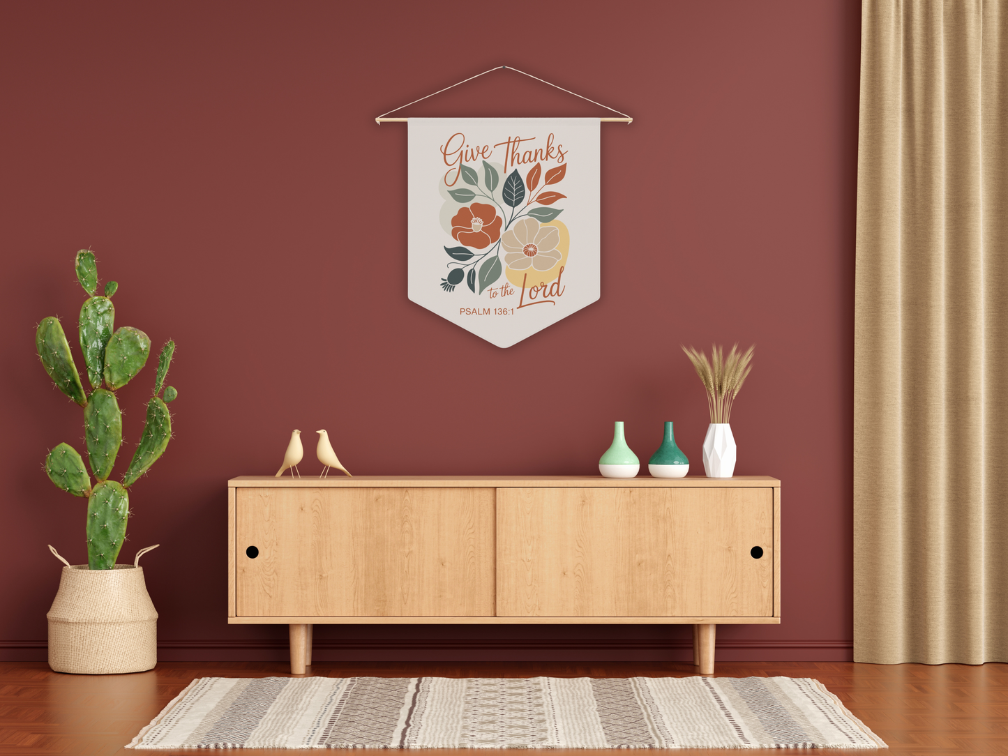Decorative wall pennant with floral design and text in a room with a wooden cabinet, plants, and a rug.