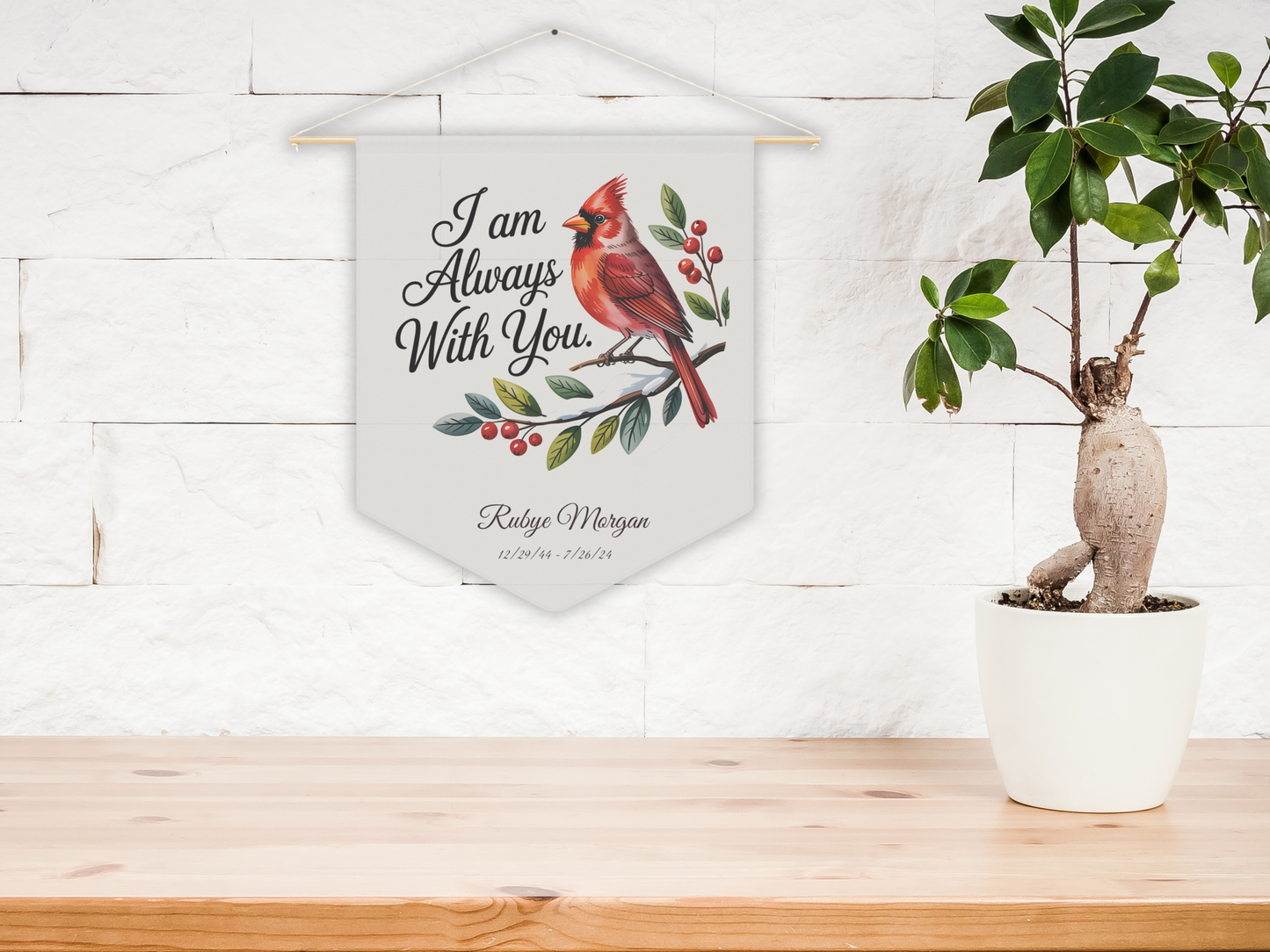 Decorative wall hanging with a cardinal bird design and text on a wooden surface with a plant.