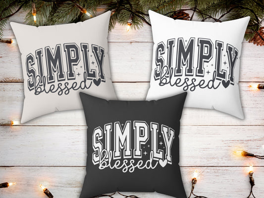 Three pillows with 'Simply Blessed' text on a wooden background with Christmas lights.