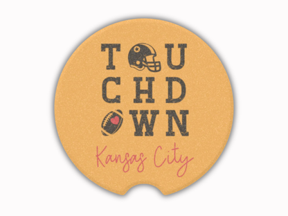 Round mustard-colored car coaster with 'Touchdown Kansas City' text and football graphics on a white background