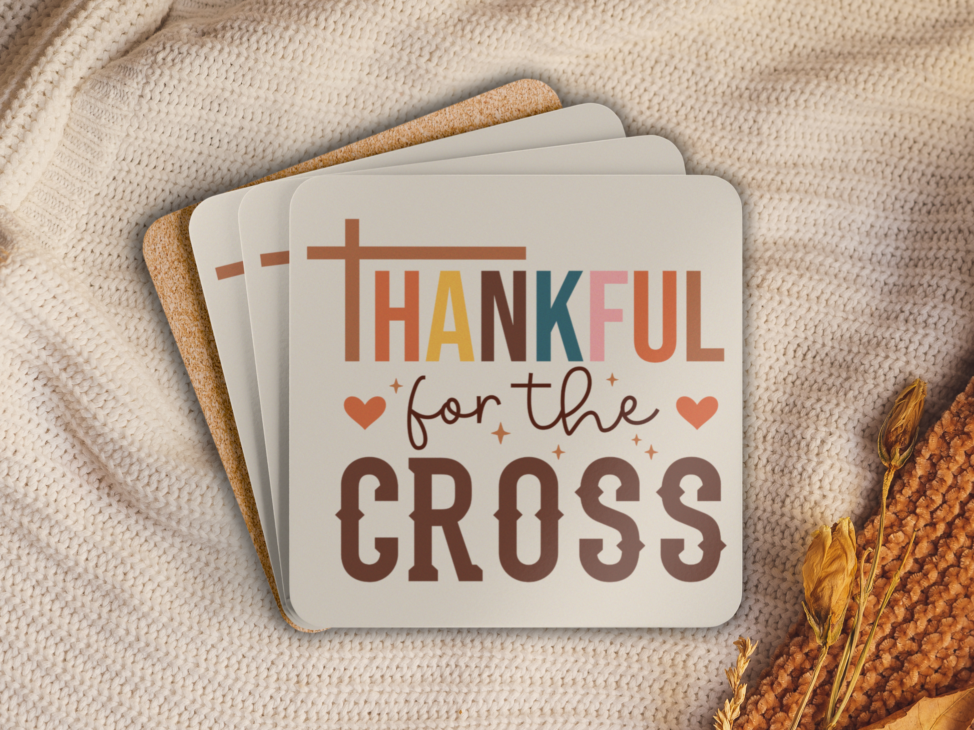 Stack of scripture coasters with cork backing placed on a cozy knit blanket with dried autumn accents.