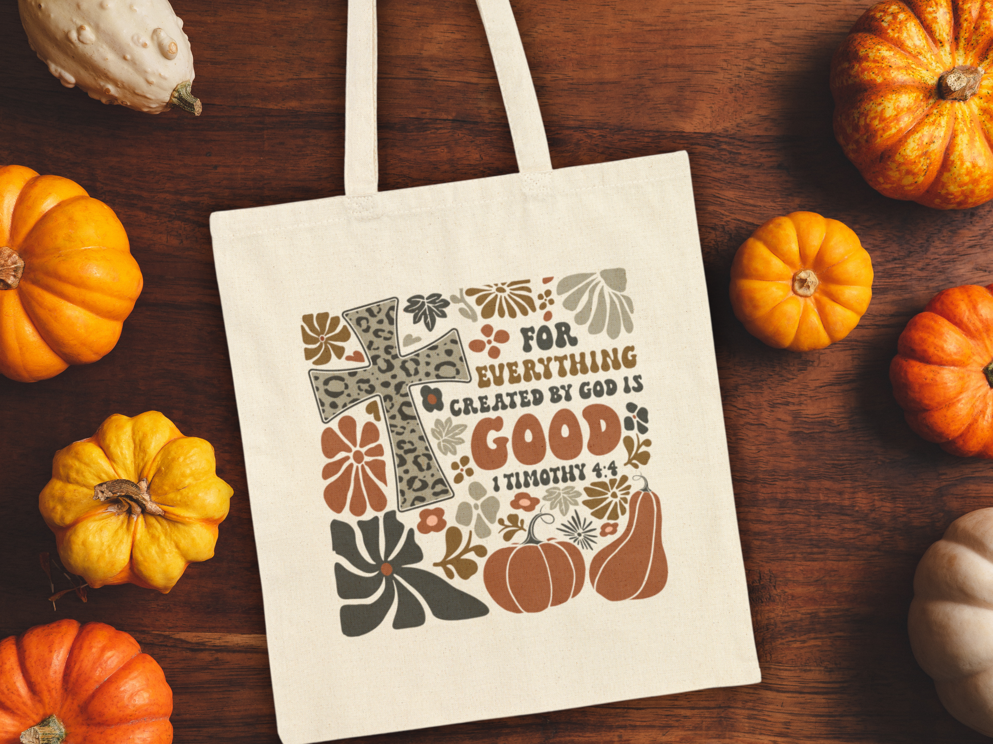 Tote bag with inspirational quote surrounded by pumpkins on a wooden surface