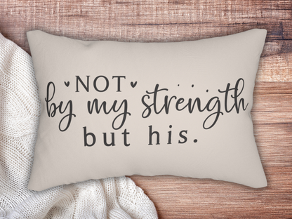 A beige pillow on a wooden surface shows a motivational quote: "Not by my strength but his." It rests beside a cozy white knit blanket, creating a warm and comforting tone.