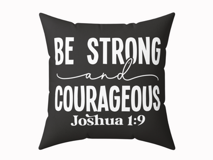 Black cushion with bold white text: "Be Strong and Courageous" in a mix of script and block fonts. Below, "Joshua 1:9" is printed in smaller text.