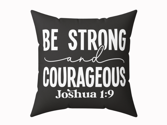 Black cushion with bold white text: "Be Strong and Courageous" in a mix of script and block fonts. Below, "Joshua 1:9" is printed in smaller text.