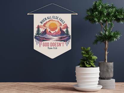 Wall pennant with a sunrise over mountains, text "When all else fails God doesn't" and "Psalm 73:26." Next to two potted plants, creating a calm atmosphere.