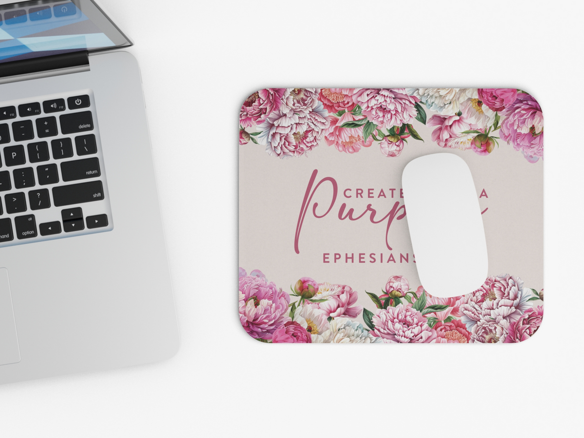 A sleek laptop beside a floral mousepad with a white mouse. The mousepad features vibrant pink and white peonies and a motivational quote.
