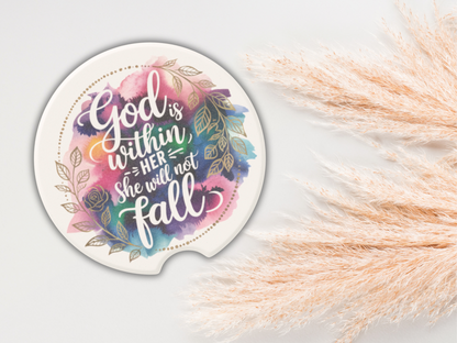 Round coaster with floral design and colorful text: "God is within her, she will not fall." Pampas grass decor on the right adds a serene touch.