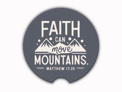 A car cup coaster with white text and mountain illustrations reads, "Faith can move mountains, Matthew 17:20," conveying inspiration and hope.