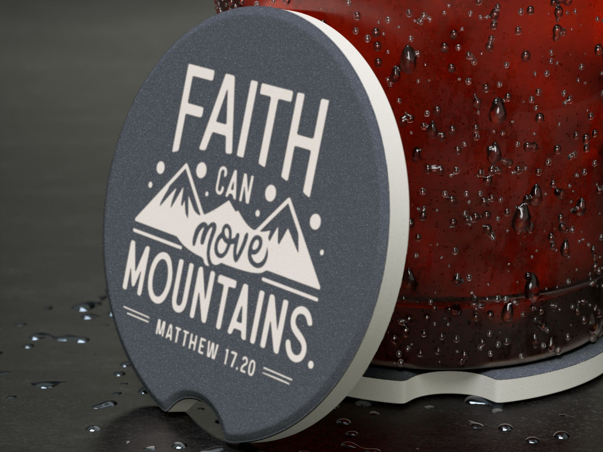 Close-up of a coaster with the text "Faith can move mountains" and "Matthew 17:20" in bold, decorative fonts. Mountains graphic beneath text.