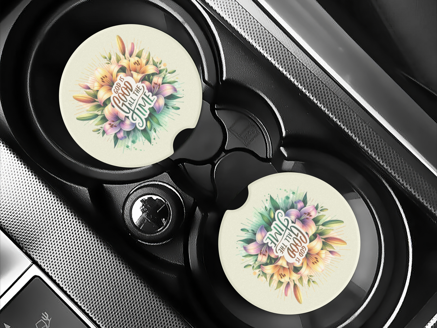 Car cup holders with round car coasters featuring colorful floral designs and the text "God is good all the time" in elegant lettering.