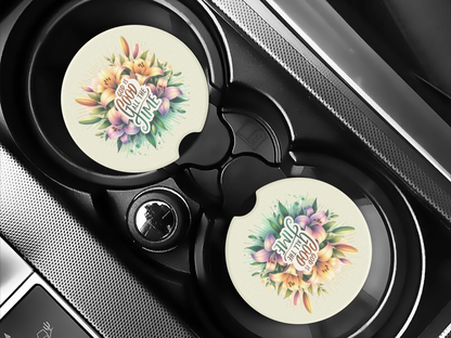 Car cup holders with round car coasters featuring colorful floral designs and the text "God is good all the time" in elegant lettering.