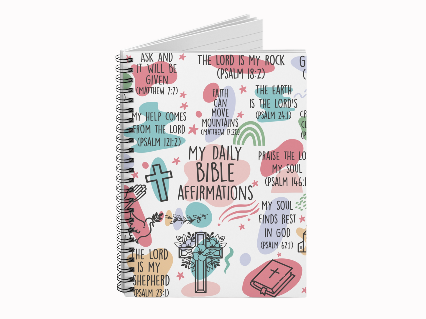 Spiral notebook with colorful illustrations and Bible affirmations. Features crosses, rainbows, and flowers on a white background, conveying inspiration.