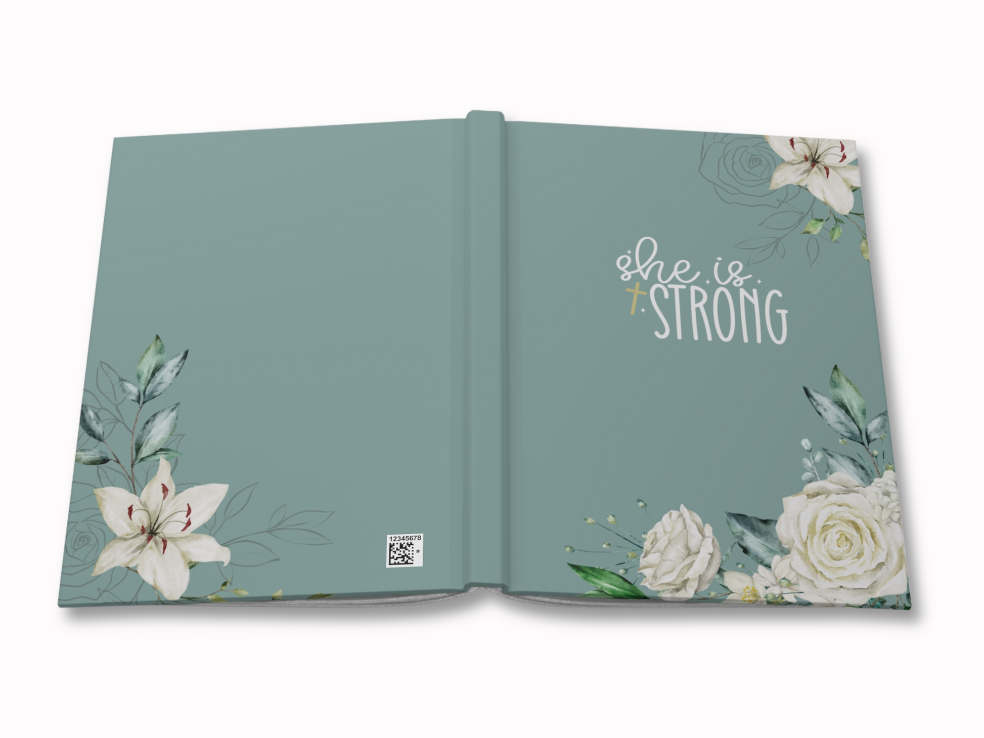 Open hardcover journal with a soft teal cover featuring delicate white flowers and leaves. The words "she is strong" are prominently displayed in elegant script.