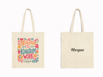 Front and back view of tote bags. The front bag displays colorful text "Motherhood is Kingdom Work" with floral designs. The back shows "Morgan" in cursive.