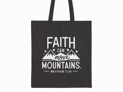 Black tote bag with a white design featuring the text "Faith can move mountains. Matthew 17.20" above simple mountain graphics, conveying inspiration.