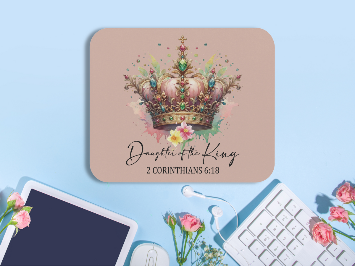 A desk with a laptop, flowers, and keyboard shows a mouse pad featuring a colorful jeweled crown. Text reads "Daughter of the King, 2 Corinthians 6:18."