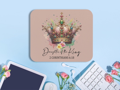 A desk with a laptop, flowers, and keyboard shows a mouse pad featuring a colorful jeweled crown. Text reads "Daughter of the King, 2 Corinthians 6:18."